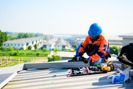 Male technician worker installing solar panels on rooftop of industrial plant