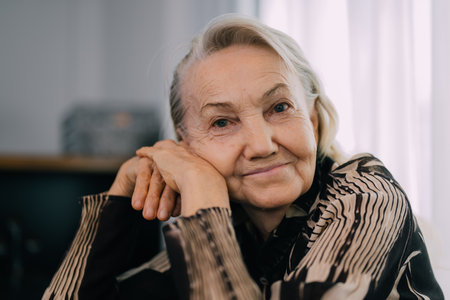 Smiling portrait of happy senior woman smiling and sitting on sofa at home