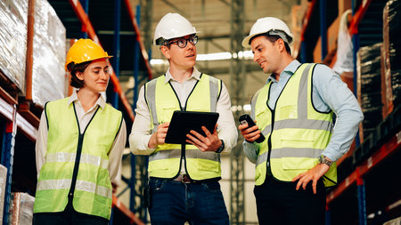 Professional warehouse workers with safety vest talking and discussing planの写真素材
