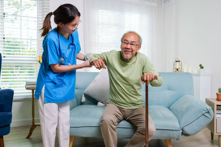 Elderly patient on sofa trying to stand and walking with caregiver nurse