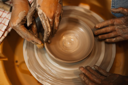 Close up on skillful hands sculpting pottery jar on potter wheel