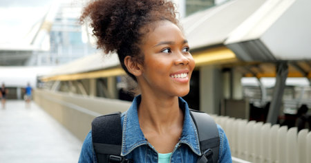 Portrait of smiling happy woman walking in street with backpackの写真素材