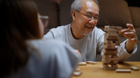 Healthy grandfather playing wooden game with granddaughter happily