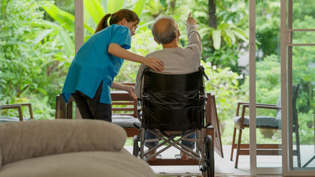 Elderly patient on wheelchair trying to stand and exercising with caregiver