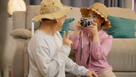 Senior woman holding digital camera taking photos of husband at homeの写真素材