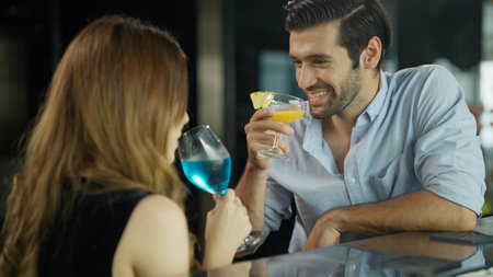 Couple of handsome man and beautiful woman drinking cocktails in luxury barの写真素材