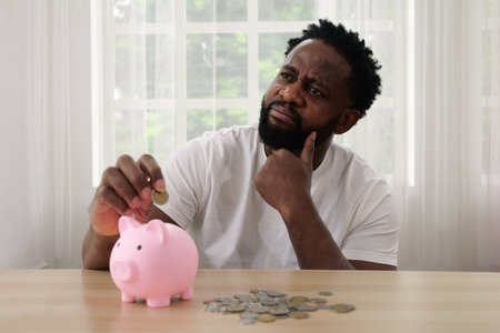 Man putting coin of cash into ceramic piggy bankの写真素材
