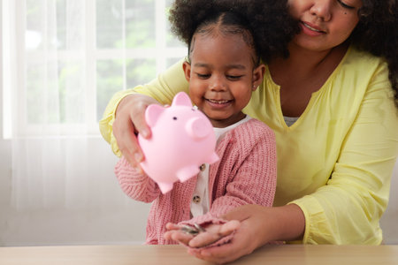 Little girl putting coin of cash into ceramic piggy bankの写真素材