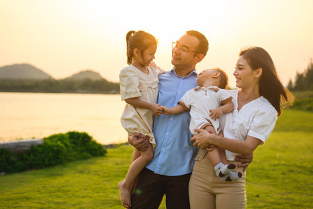 Happy family enjoying in park together on weekend with sunset viewの写真素材