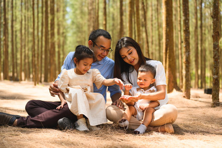 Smiling father and mother spending travel time with children at parkの写真素材