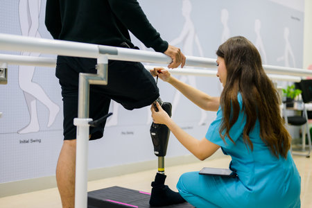 Nurse helping patient to walk between barbells at health care centerの写真素材