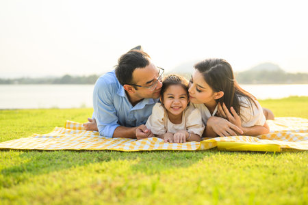 Happy family relaxing and resting in park together on weekendの写真素材