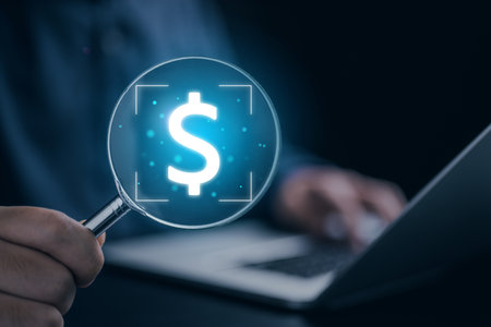 Businessman using laptop and holding magnifier with dollar signの写真素材