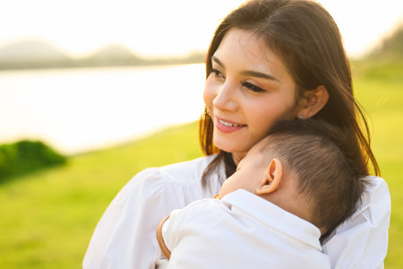 Loving mother holding and carrying her newborn baby at public park