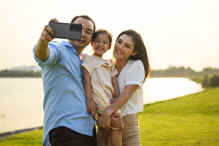 Family taking selfie photo together with green meadow and river viewの写真素材