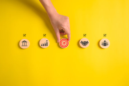 Hand putting business icons on wooden cubic blocks