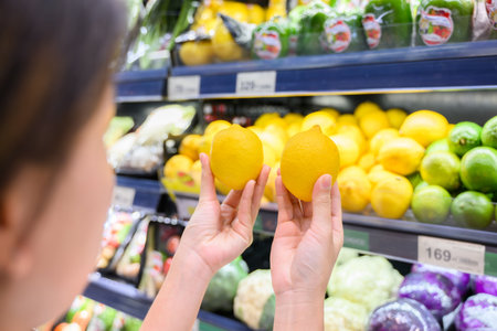 Young adult woman using phone in grocery storeの写真素材