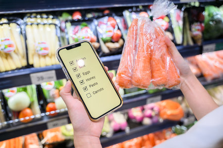 Young adult woman using phone in grocery storeの写真素材