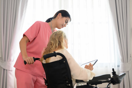 Happy doctor talking with elderly patient at home visitの写真素材