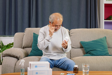 Senior man looking and reading label of medicine at home