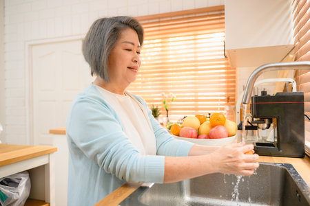 Happy woman cleaning fruits at kitchen. Happy senior cleaning fruit.の写真素材