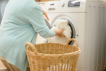 a beautiful senior woman, takes care of the laundry using a washing machineの写真素材