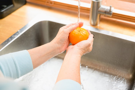 Happy woman cleaning fruits at kitchen. Happy senior cleaning fruit.の写真素材