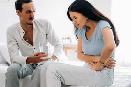 Young wife with health problem at home, Husband taking care of wifeの写真素材