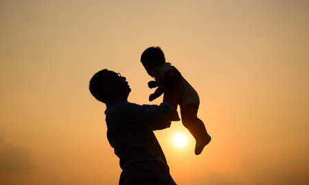 Silhouette shot of happy father holding newborn baby with sunset viewの写真素材