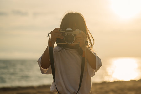 Portrait of girl holding camera taking photos on beachの写真素材
