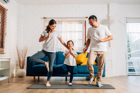Father mother and daughter doing exercise in living room at homeの写真素材