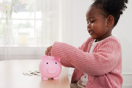 Little girl putting coin of cash into ceramic piggy bankの写真素材