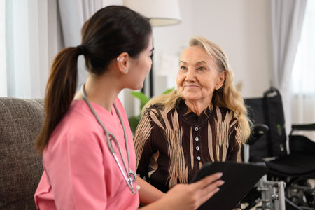Female doctor talking with elder patient at home visitの写真素材