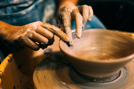 Craftsman potter making jug of clay on potter wheel circle in workshopの写真素材