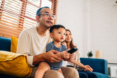 Happy family watching television together at living roomの写真素材
