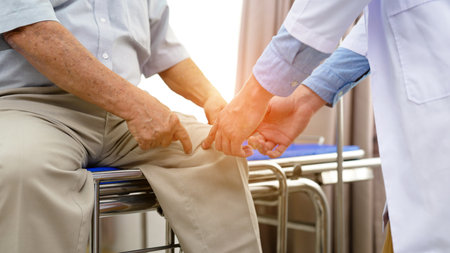 Doctor visiting and checking legs of senior man patientの写真素材