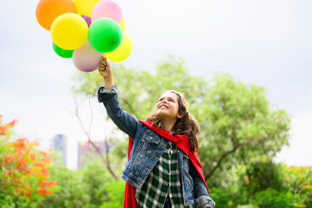 Happy girl holding colorful air balloons playing in parkの写真素材