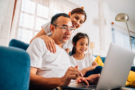 Family father mother and daughter using laptop and surfing internetの写真素材