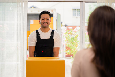 Young woman accepting and holding delivery parcel boxes from deliveryman at home, Delivery service at homeの写真素材