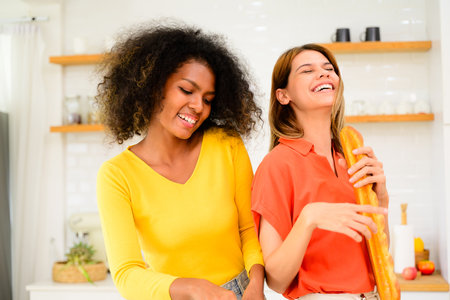 Happy lesbian couple cooking in kitchen at home, Women preparing dinner on first dating, Couple of female lovers spending time together at home, People with good relationshipの写真素材