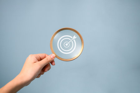 Hand holding magnifying glass with goal icon, Goal achievement and successful business target,...
