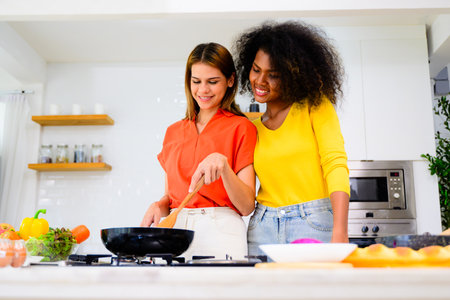 Happy lesbian couple cooking in kitchen at home, Women preparing dinner on first dating, Couple of female lovers spending time together at home, People with good relationshipの写真素材