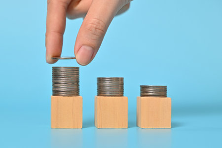 Hand arranging rows of coins on wooden cubes, Financial business investment, Growing money, People...