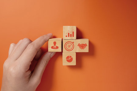 Hand putting business icons on wooden cubic blocksの写真素材