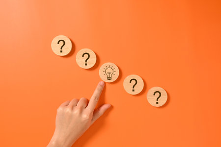 Hand with virtual light bulb and question mark icons on wooden blocks for new inspiration of new business, Creative idea for businessの写真素材