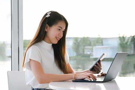 A female freelancer is working using a laptop on a working plane. The photo is of high quality.