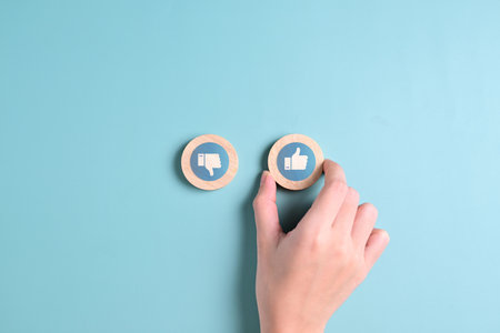 Wooden cubes with like and dislike hand, Hand choosing between happy and unhappy, Thumb up and thumb down, Customer service experience and satisfaction survey, Disagreement and agreement expressionの写真素材