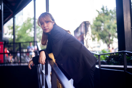 Blond hair woman with half-tied hair bend down herself on the handrail of the slope path in the shopping mall after work.の写真素材