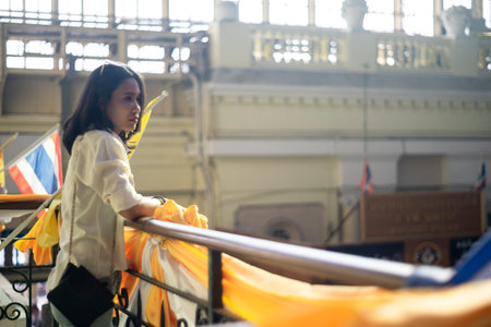 Wavy hair woman in white shirt standiinf on the second floor of train station, prop her elbow on the handrail waiting for her friend of this trip.の写真素材