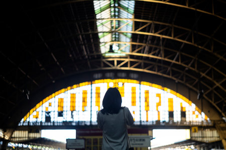 Back shot of wavy hair woman in white shirt look at the dome structure of train station with sunlight, silhouette.の写真素材